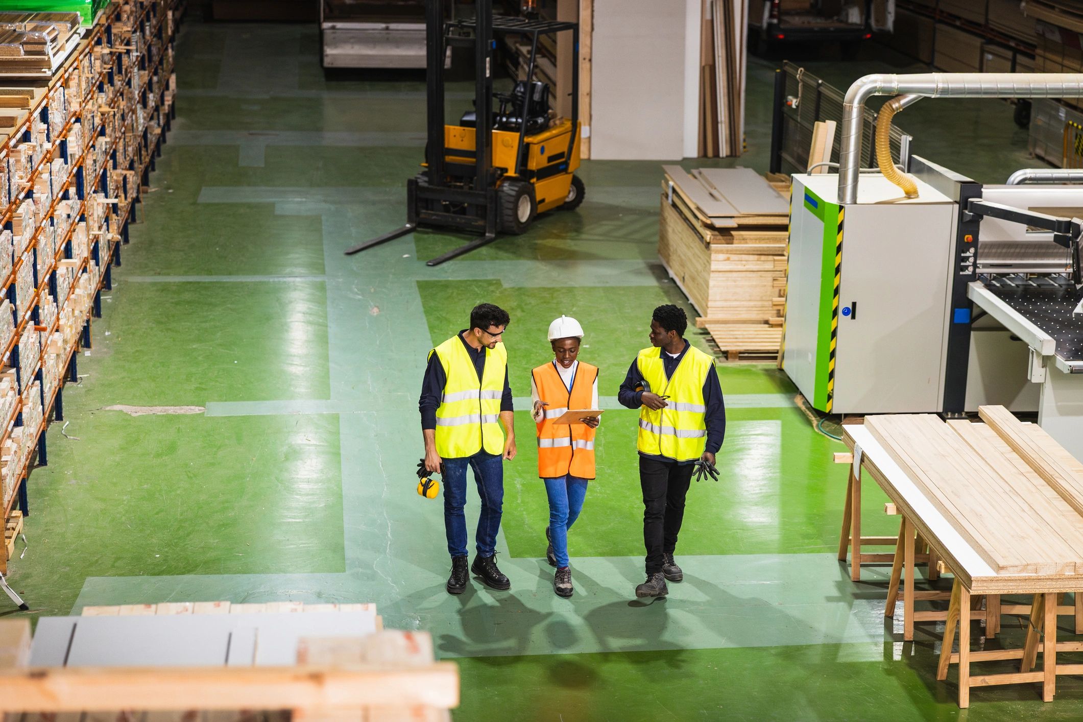 Workers walking through a lumberyard warehouse